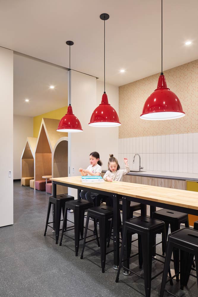 Next to the kid play area is this kitchen area with a long bar table and bar stools, with red pendants hanging above