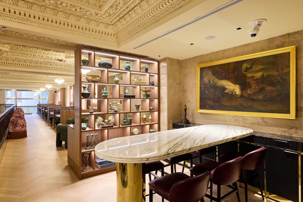 A section of the mezzanine with a bar height table placed behind a modern shelf for privacy that separates this area from the resto of the lounge