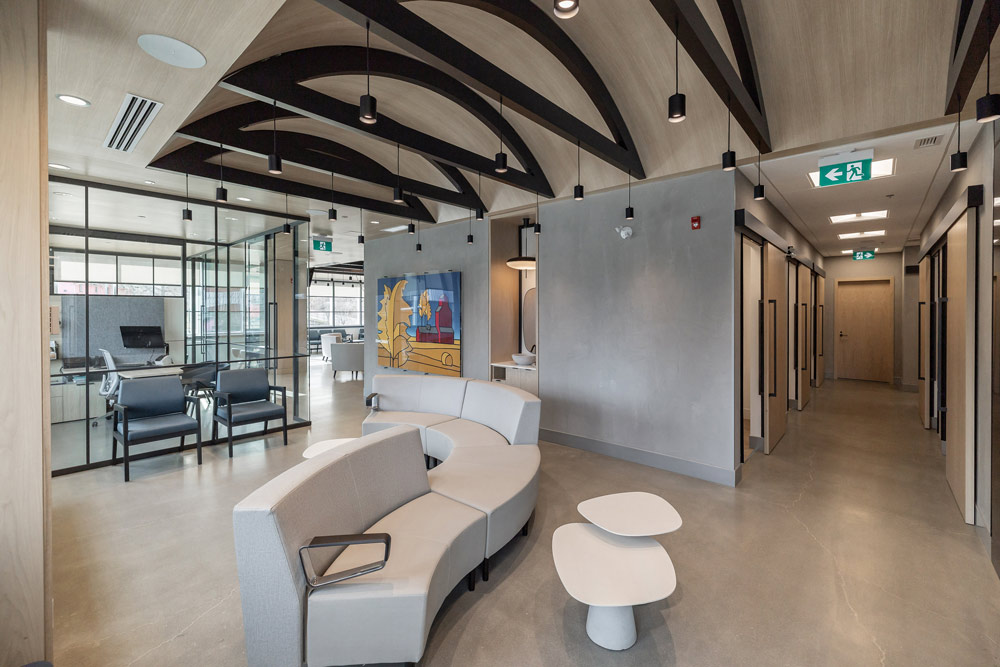 Curved sofa in the reception area and above it is an arched ceiling and black details inside the arch. Another indigenous art piece is hanging on the wall