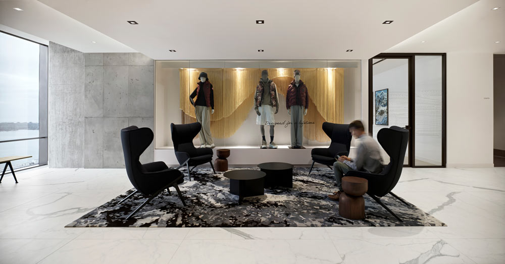 A central lounge area in the middle of a light and bright space, and a display window with three mannequins built in the wall