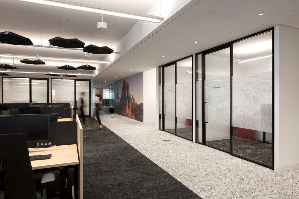 Working station area right next to offices enclosed behind glass walls. Colour scheme is black and white