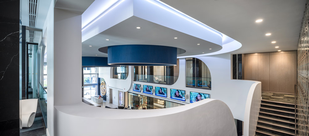 The View from the mezzanine where the offices are located toward the central double floor height area and the futuristic elements like the white curvs and blue circular lighting elements on the ceiling