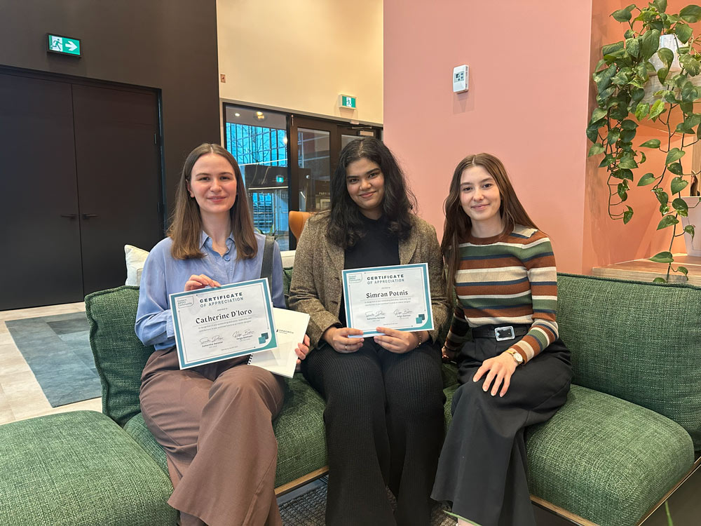 Catherine D’iorio and Simran Potnis posing on camera while sitting down, with their certifications