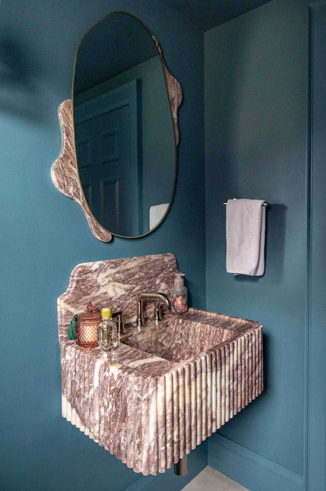 in a deep blue hue, it features a custom fluted Purple Lilac marble sink and matching mirror