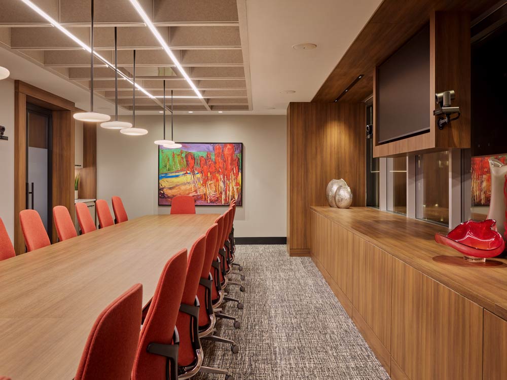Conference room with warm red details throughout and wooden finishes on shelves and the desk